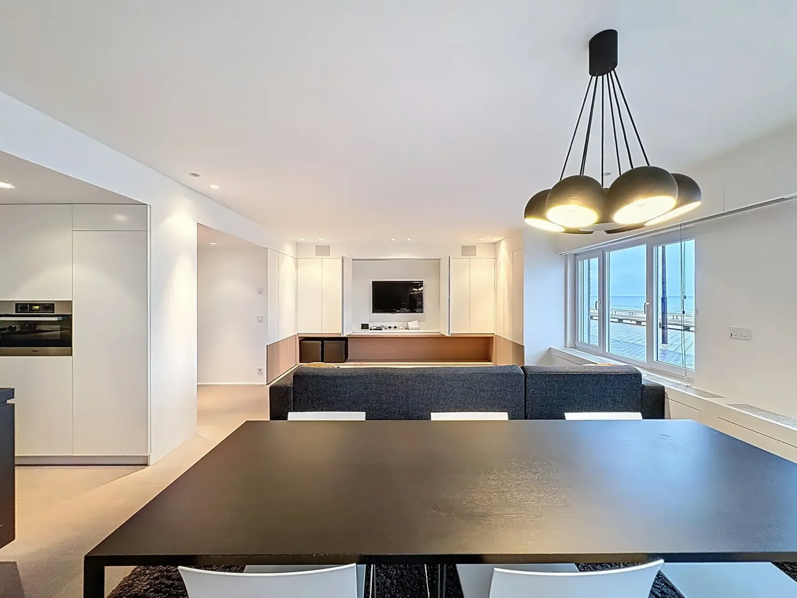 Eettafel voor de ramen met zeezicht in het appartement in De Haan